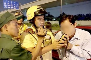 A traffic police officer measures breath alcohol concentration of a driver. (Photo: Sggp)