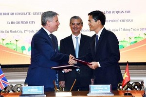 Ian Gibbons, Consul General of the UK in Ho Chi Minh City ( L) and director of the HCMC’s Department of Transport, Tran Quang Lam hands over agreements. (Photo: VNA)