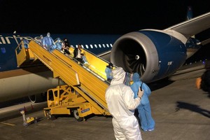 Vietnamese people return home on a repatriation flight in Van Don Airport. (Photo: SGGP)