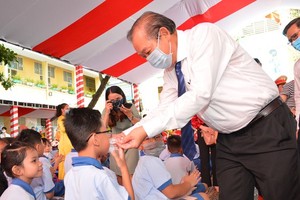 Deputy Prime Minister Truong Hoa Binh helps a student to wear face mask. (Photo: SGGP)
