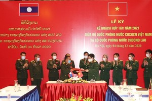 The defence ministers of Vietnam and Laos exchange the signed 2021 cooperation plan in Hanoi on December 4 (Photo: VNA)