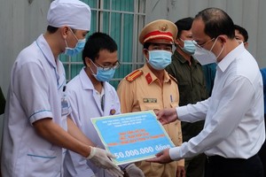 Deputy Secretary of the HCMC Party Committee Nguyen Ho Hai presents gifts to the Covid-19 control station at the Doi Bridge in Binh Chanh District. (Photo: SGGP)