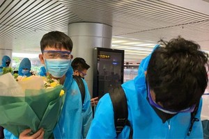 Midfielder Luong Xuan Truong (L) receives flowers from Vietnamese fans at the airport. (Photo: SGGP)