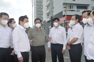 Prime Minister Pham Minh Chinh (C) inspects the epidemic prevention and control at a quarantine facility in the dormitory of the Vietnam National University HCMC. (Photo: SGGP)