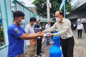 Vice secretary of the City Party Committee Nguyen Ho Hai presents each family whose houses burned in the fire a financial support of VND5 million. (Photo: SGGP)