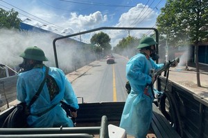 Soldiers in protective gear using high-pressure sprays sanitize streets in Binh Tan District on July 18. (Photo: SGGP)