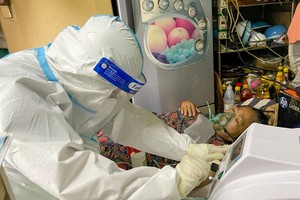 A healthcare worker of the Nguyen Cu Trinh Ward is taking care a Covid-19 patient at home. (Photo: SGGP)