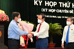 Secretary of the Party Committee of HCMC Nguyen Van Nen (C) and Mr. Nguyen Thanh Phong (R) offer flowers to Mr. Phan Van Mai. (Photo: SGGP)