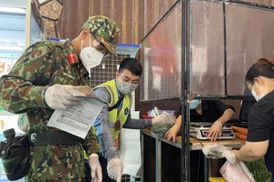 Military forces help local residents shop for food during the stricter social distancing measures. (Photo: SGGP)