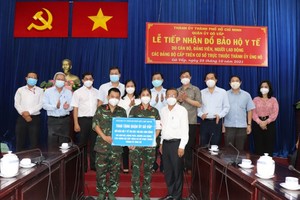 Head of the HCMC Party Committee's Commission for Mass Mobilization Nguyen Huu Hiep (R)  presents gifts to Goa Vap District. (Photo: SGGP)