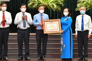 Chairwoman of the HCMC People’s Council, Nguyen Thi Le hands over the Certificate of Merit from the Prime Minister to the HCMC Party Committee's Commission for Mass Mobilization.