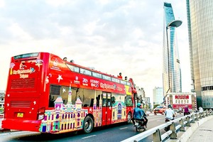 ​Visitors take hop-on hop-off bus tour in HCMC.