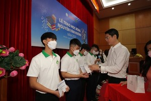 A representative of a sponsor of the event hands over scholarships to students. 