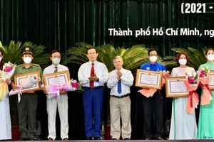 Secretary of HCMC Party Committee Nguyen Van Nen (4th, L) presents certificates of merit to outstanding individuals and collectives .