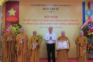 Vice Secretary of the Party Committee of HCMC Nguyen Ho Hai hands over a certificate of merit from the Prime Minister to the Executive Board of the Vietnam Buddhist Sangha (VBS) of District 3 .
