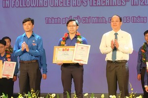 Secretary of the Central Committee of the Youth Union Nguyen Minh Triet (L) and Vice Secretary of the municipal Party Committee Nguyen Ho Hai (R) present certificates of merit to outstanding youth.