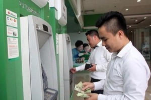 Office workers withdraw money from an ATM. (Photo: VNA)