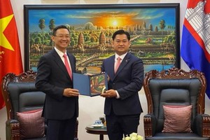 Cambodian Consul General to HCMC Sok Dareth (R) hands over a gift to  Director of the municipal Department of Foreign Affairs Tran Phuoc Anh.
