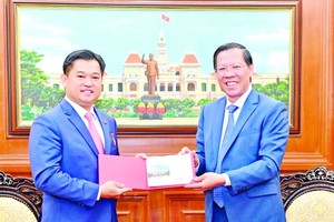 Chairman of the HCMC People’s Committee Phan Van Mai (R) hands over the HCMC badge to outgoing Cambodian Consul General in HCMC Sok Dareth. (Photo: SGGP)