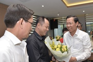 Chairman of the HCMC People’s Council Phan Van Mai offers flowers to members of the HCMC’s Council of Presidents of Universities. (Photo: SGGP)