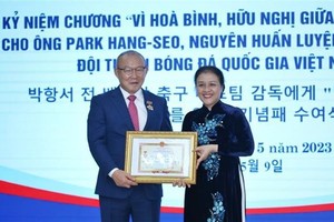 Ambassador Nguyen Phuong Nga (right) presents the insignia to coach Park Hang-seo. (Photo: VNA)