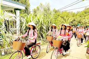 Cambodian and Laotian students take a ride on bicycles in the island commune of Thanh An in Can Gio District. (Photo: SGGP)
