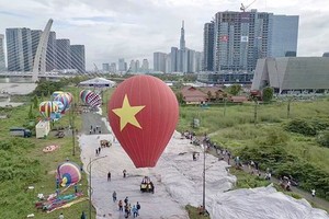 A hot-air balloon with a height of 18 meters and a diameter of 14 meters carrying a national flag flying high in the sky over HCMC (Photo: SGGP)