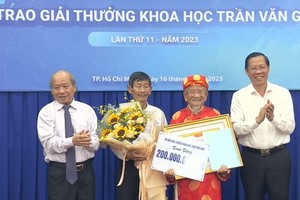 Chairman of the HCMC People’s Committee Phan Van Mai (R) and a representative of the Committee of the Tran Van Giau Awards offer the prize to researcher Nguyen Dinh Tu (C). (Photo: SGGP)