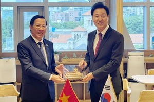 Chairman of the HCMC People's Committee Phan Van Mai (L) offers a gift to Mr. OH Se Hoon, Mayor of Seoul. (Photo: SGGP)