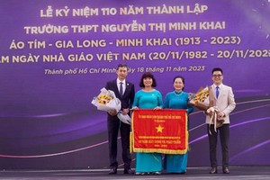 Chairwoman of the HCMC People’s Council Nguyen Thi Le presents the Flag of Tradition to the school Board of Directors of the Nguyen Thi Minh Khai High School. (Photo: SGGP)