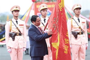 PM Pham Minh Chinh attaches the symbol of the “Hero of the People’s Armed Forces” title to the traditional flag of the Mobile Police Force. (Photo: VNA)
