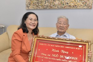 Chairwoman of the HCMC People’s Council Nguyen Thi Le (L) offers a gift to former head of the Mobile Medical Team II Ngo Duy Doan. (Photo: SGGP)