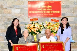 Chairwoman of the HCMC People’s Council Nguyen Thi Le (L) presents 60-year Party membership badges to former director of the Department of Public Security Tran Van Tao and his wife, Tran Thi Ngoc. (Photo: SGGP)