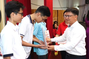Head of the HCMC Party Committee's Commission for Mass Mobilization Nguyen Manh Cuong offers financial aids to underprivileged students. (Photo: SGGP)