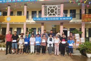 Representative of the SGGP Newspaper offers gifts to students and their parents of the Xuan Hoa semi-boarding secondary school for ethnic minority groups. (Photo: SGGP)