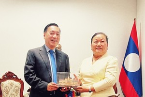 Vice Chairman of the HCMC People's Council Pham Thanh Kien offers a gift to a leader of the Vientiane People's Council. (Photo: SGGP)