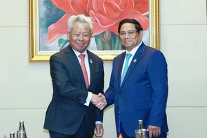 Prime Minister Pham Minh Chinh (right) receives President of the Asian Infrastructure Investment Bank (AIIB) Jin Liqun in Vientiane on October 10. (Photo: VNA)