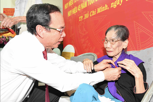 Secretary of the of the HCMC Party Committee Nguyen Van Nen offers the Party membership badge to a senior Party member. (Photo: SGGP)