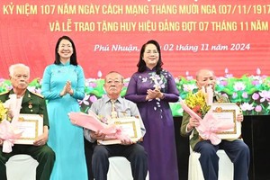 Head of the HCMC Party Committee's Inspection Commission Tran Kim Yen (R) and Secretary of the Party Committee of Phu Nhan District Phan Thi Thanh Phuong (L) present the Party membership badges to veteran Party members. (Photo: SGGP)