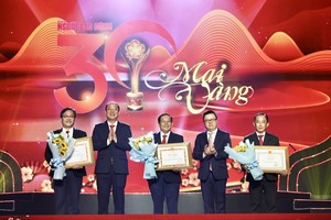 Head of the Central Propaganda and Education Committee cum chairman of the Vietnam Journalists Association, Editor-in-Chief of the Nhan Dan Newspaper Le Quoc Minh (2nd, R), and Standing Vice Secretary of the Ho Chi Minh City Party Committee Nguyen Ho Hai (2nd, L) offer certificates of merit of the Ministry of Information and Communication, and the Ho Chi Minh City Party Committee to the Nguoi Lao Dong Newspaper for the outstanding achievement in organizing the Mai Vang Awards during 30 years. (Photo: SGGP)