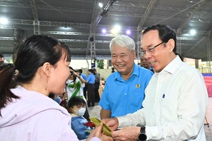 Secretary of the municipal Party Committee, Nguyen Van Nen (R) extends Tet greetings to workers on January 26. (Photo: SGGP)