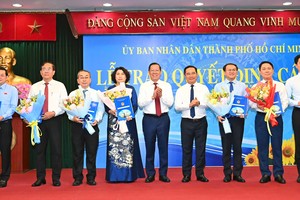 Head of the newly formed Economic and Financial Committee Phan Van Mai (5th, R) and Vice Secretary of the HCMC Party Commitee, Nguyen Van Duoc (4th, R) hand over the appointment decision to directors of seven newly established departments. (Photo: SGGP)