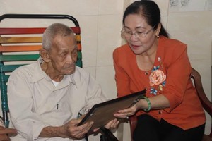 Chairwoman of the Ho Chi Minh City People’s Council Nguyen Thi Le presents a reconstructed portrait of the martyr Nguyen Ngoc Khanh to his father. (Photo: SGGP)