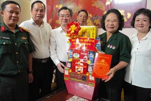 Standing Vice Secretary of the HCMC City Party Committee Nguyen Thanh Nghi (3rd, L) offers a gift to Mrs. Phuong Ngoc Hanh (2nd, R). (Photo: SGGP)