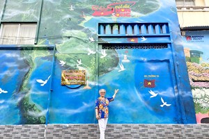 居民高兴地在第一郡阮泰学小学的「美丽越南」壁画前拍照留念。