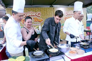 游客在“2025年岘港美食之旅”美食节上体验做煎饼的乐趣。