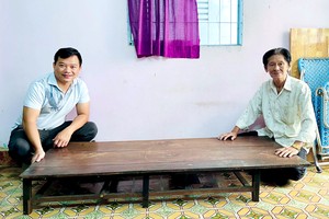 梁建刚（右）向笔者捐赠其父母留下来拥有80多年历史的裁床。