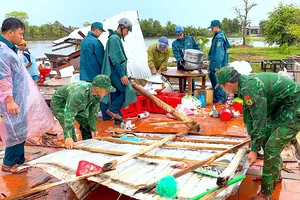 Cán bộ, chiến sĩ Đồn biên phòng Khánh Tiến cùng lực lượng Quân sự xã U Minh hỗ trợ hộ người dân che chắn lại nhà sau thiên tai. ẢNH: HOÀNG TÁ