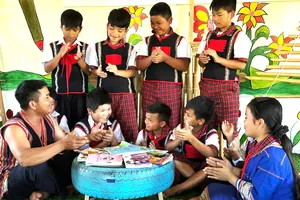 Anh A Áo (bìa trái) hướng dẫn học sinh ở xã Tu Mơ Rông, tỉnh Quảng Ngãi cách hát ting ting (Ảnh: THANH XIÊNG)