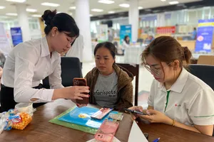 Nhân viên ngân hàng hỗ trợ hộ kinh doanh về công nghệ thông tin (Ảnh: PHÚ NGÂN)